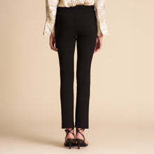 Person wearing black pants and a patterned top on a beige background