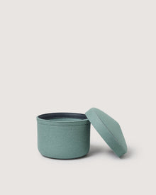 A small, round, light teal Merino wool bin by Graf Lantz is shown with its matching removable lid beside it against a plain white background.