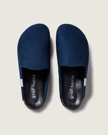 Dark blue Merino wool slippers by graf lantz, featuring black insoles with white graf lantz branding, closed toes, recycled rubber soles, and a slip-on design are set against a light gray background.