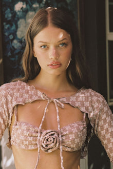 Mauve lace crop top with short puffed sleeves, tie-front closure, and rose appliqué detail at center.