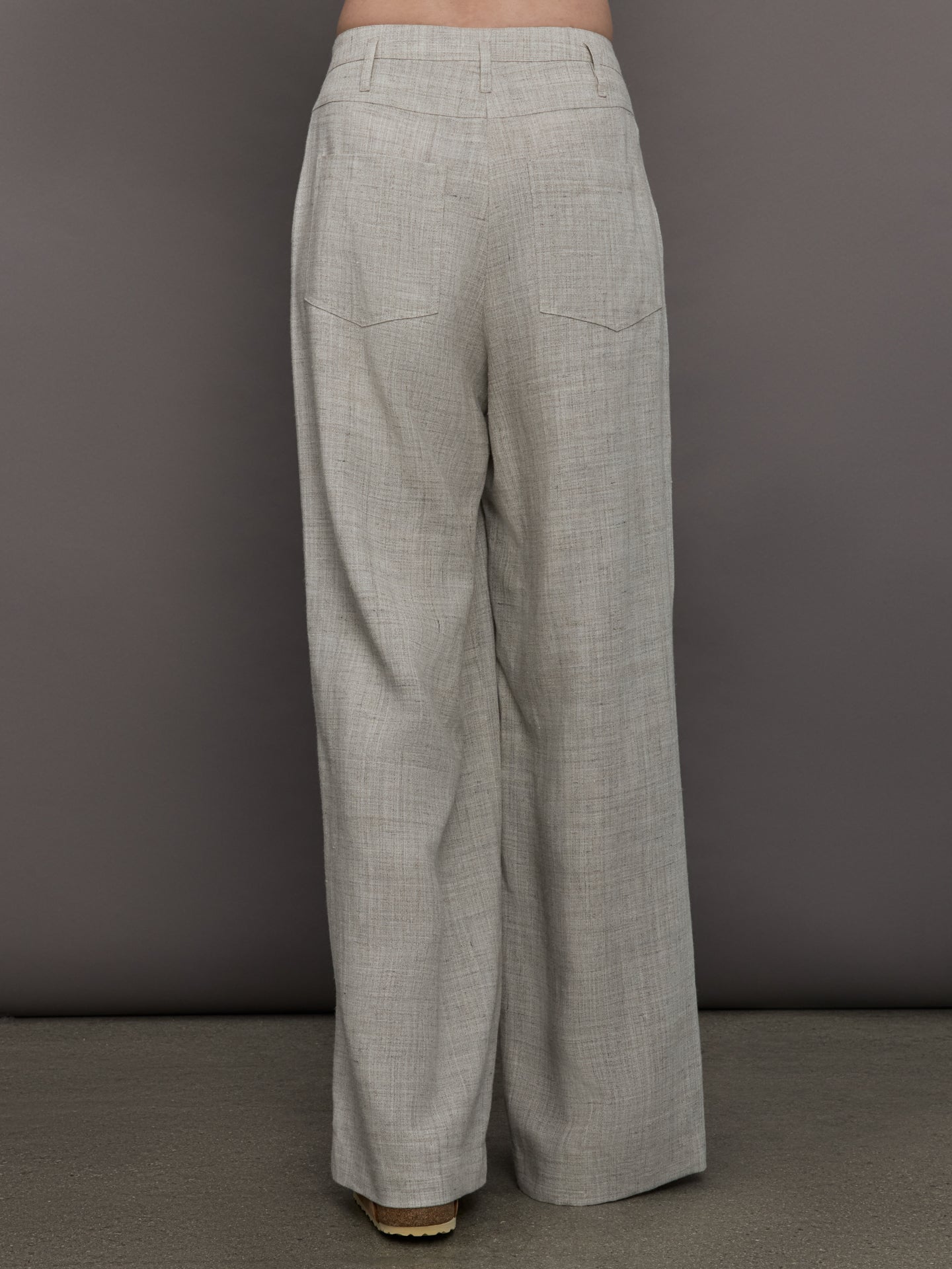 Model wears a pair of gray/taupe oversized wide leg woven work trousers.