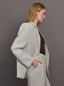 Model wears a gray/taupe textured oversized blazer with single button closure.