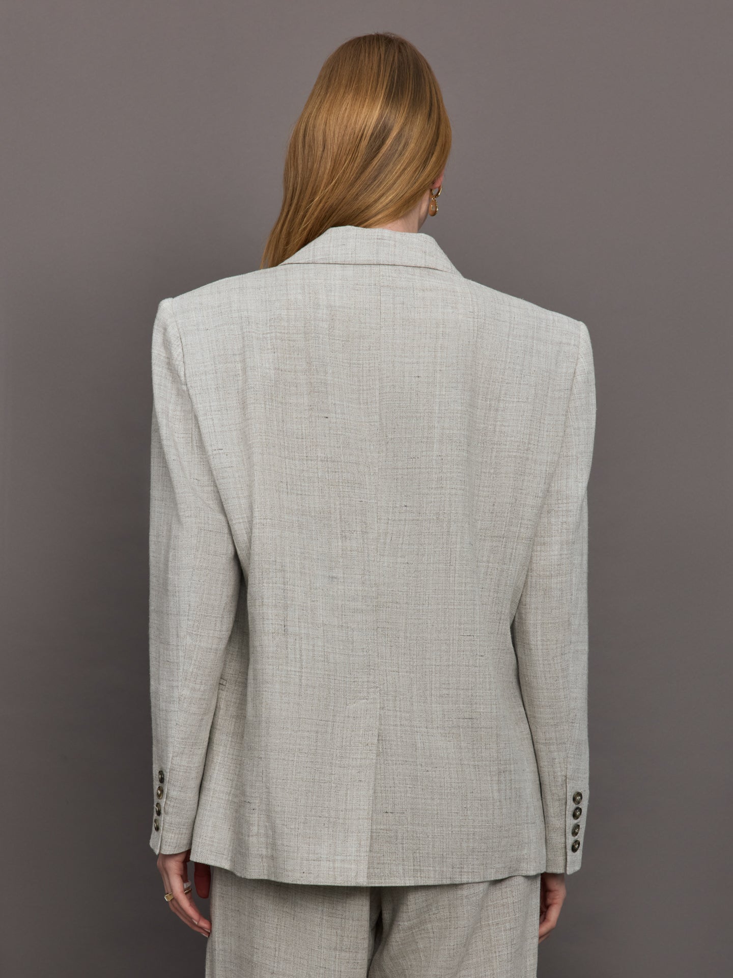 Model wears a gray/taupe textured oversized blazer with single button closure.