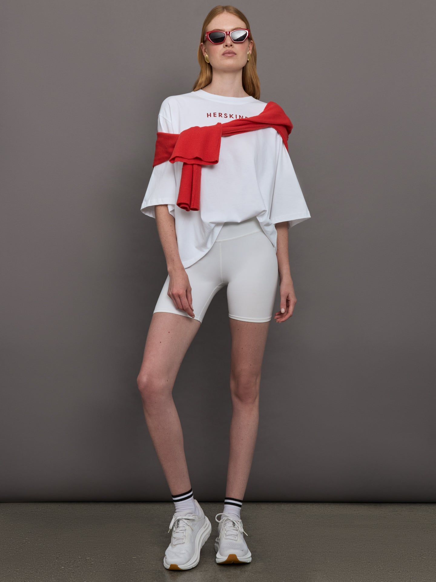 Model wears an oversized wide sleeve white tee shirt with red Herskind lettering across the chest.
