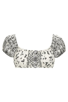 Cream-colored bandana bikini top with mixed black botanical and paisley print, puffed short sleeves, and ruched center panel.