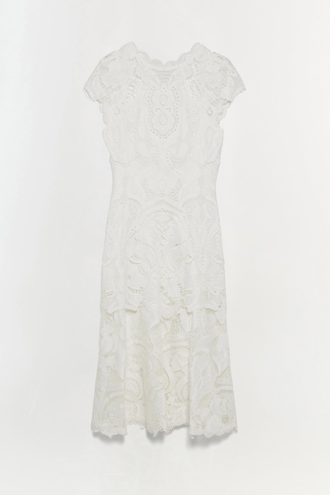 White lace dress with short sleeves, intricate floral patterning throughout, and asymmetrical handkerchief hem.