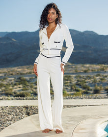 Woman in a white outfit standing in front of mountainous landscape
