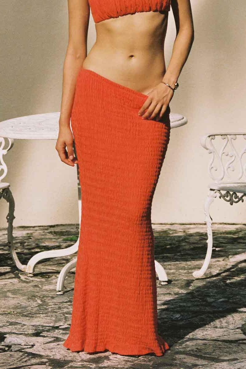 Tangerine ribbed maxi skirt with ruched texture, floor-length silhouette, worn with matching crop top.
