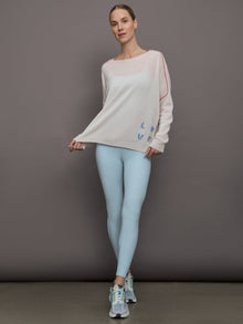 Model wears a white sweater with red seams along the biceps and blue block lettering on front bottom right that says LOVE. Back of sweater says in blue lettering 