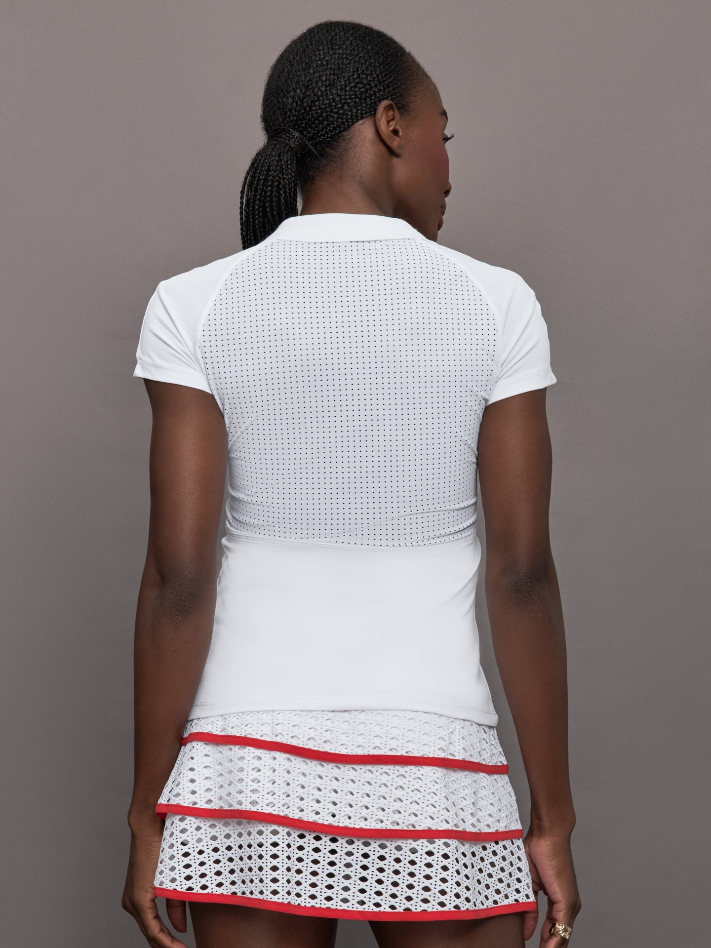 Model wears a mesh short sleeved lightweight tennis polo with red detailing.