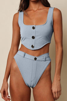 Light blue denim corset crop top with square neckline and dark button front closure, worn with matching high-waisted bottoms.