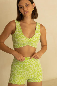 Lime green sleeveless crop top with geometric jacquard pattern and ruched front detail.