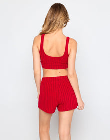 Woman wearing a cozy, red ribbed knit lounge set consisting of a cropped tank top and matching high-waisted drawstring shorts