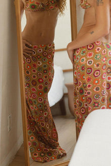 Tan silk skirt with multicolored floral print in red, pink, green, and gold tones.