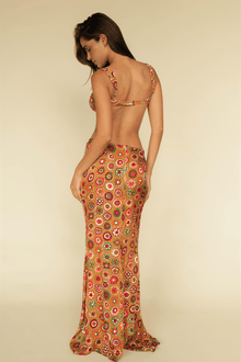 Long silk skirt with multicolor floral print in red, orange, and green tones on a tan background.