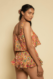 Sleeveless crop top with square neckline and multicolored floral print in red, orange, and green on tan background.