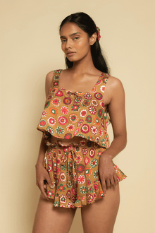 Sleeveless crop top with square neckline and multicolored floral pattern on tan background, styled with matching shorts.