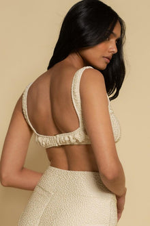Oat-colored textured sport top with sleeveless design and open back, shown from rear view.