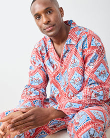 Seated close view of Reindeer Games pajama set with red framed reindeer print, button-front top, and patch pocket