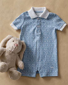 The Baby's Pima Louis Play Romper in Hoppy Days Blue is a light blue short-sleeve romper with a white collar and sleeve cuffs, a white bunny outline pattern, and bottom snaps for easy changing.