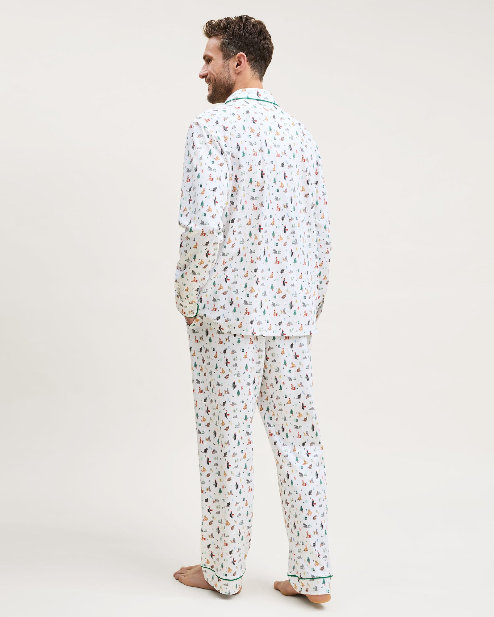 Men's Pima Pajama Set in Merry Meow: white set with green piping, featuring an all-over print of playful colorful cats. Includes a long-sleeve button-up shirt with chest pocket and matching pants.