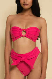Bright pink bandeau bikini top with gathered fabric and center cutout detail on model.