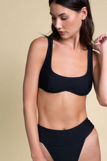 Black sport bikini top with wide shoulder straps and scoop neckline on model against neutral background.