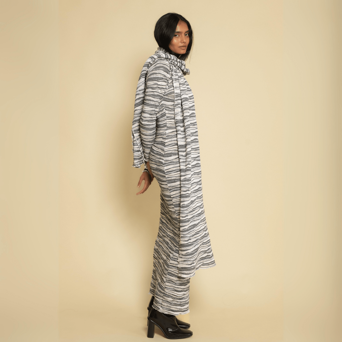 Gray and white striped knit scarf draped over person's shoulder, extending to ankle length.