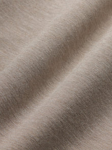 Model wears a taupe heather colored, long-sleeve knit sweatshirt with a wide neck.