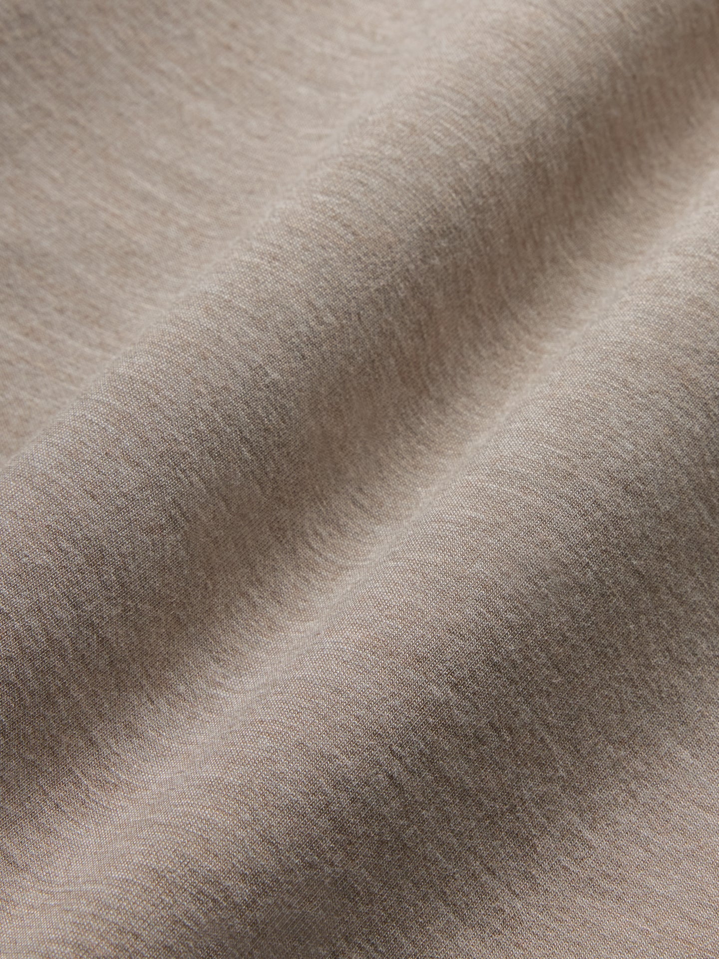 Model wears a taupe heather colored, long-sleeve knit sweatshirt with a wide neck.