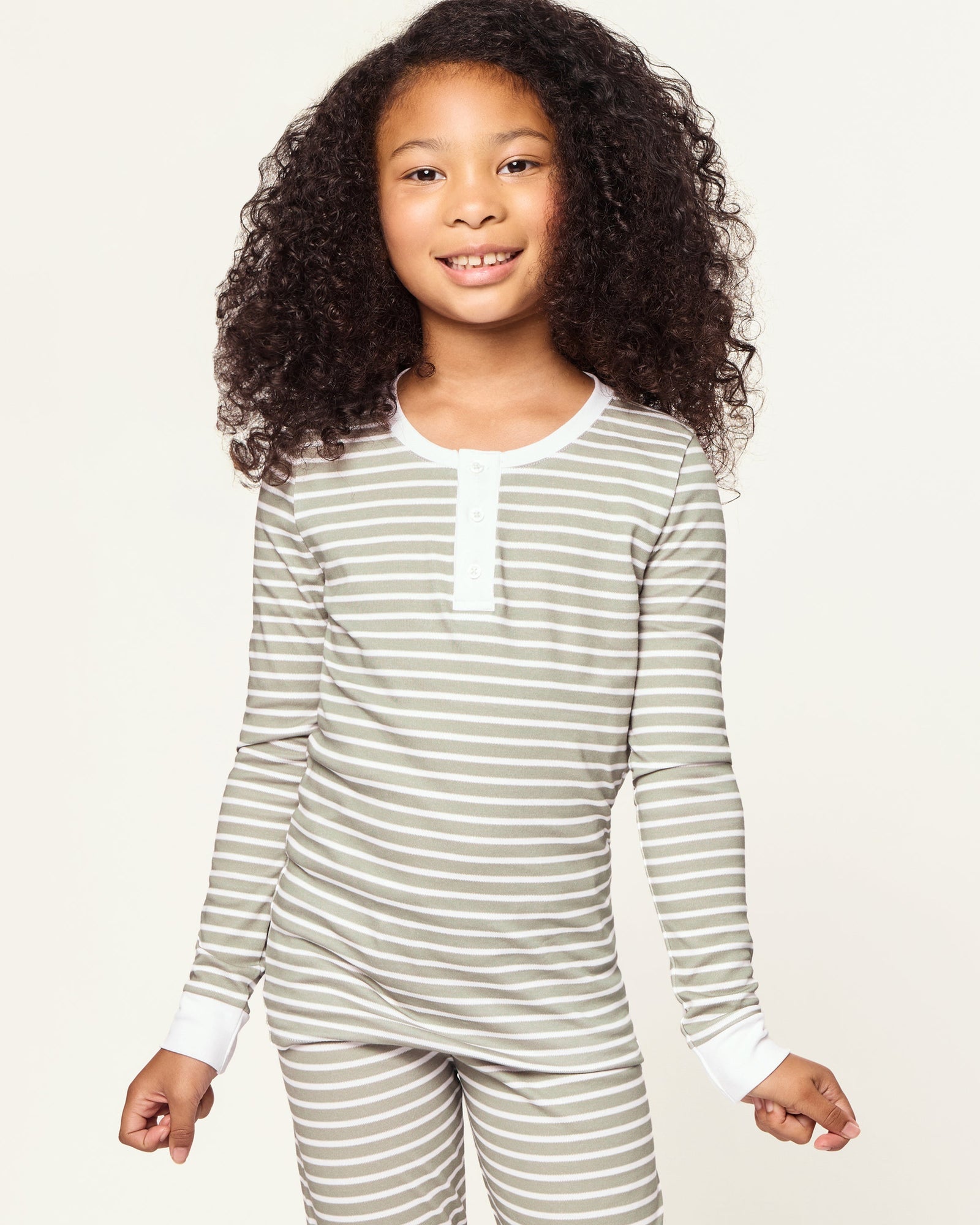 The Kid's Pima Snug Fit Pajama Set in Sage Stripe features green and white horizontal stripes, long sleeves, white cuffs at wrists and ankles, and a small button placket on the shirt. The set is displayed flat on a white background.