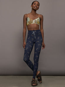 Model is wearing a paisley v neck sports bra with brown, white, and blue coloring. 