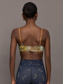 Model is wearing a paisley v neck sports bra with brown, white, and blue coloring. 