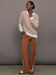 Model is wearing a brown/white horizontally striped oversized sweater.