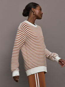 Model is wearing a brown/white horizontally striped oversized sweater.