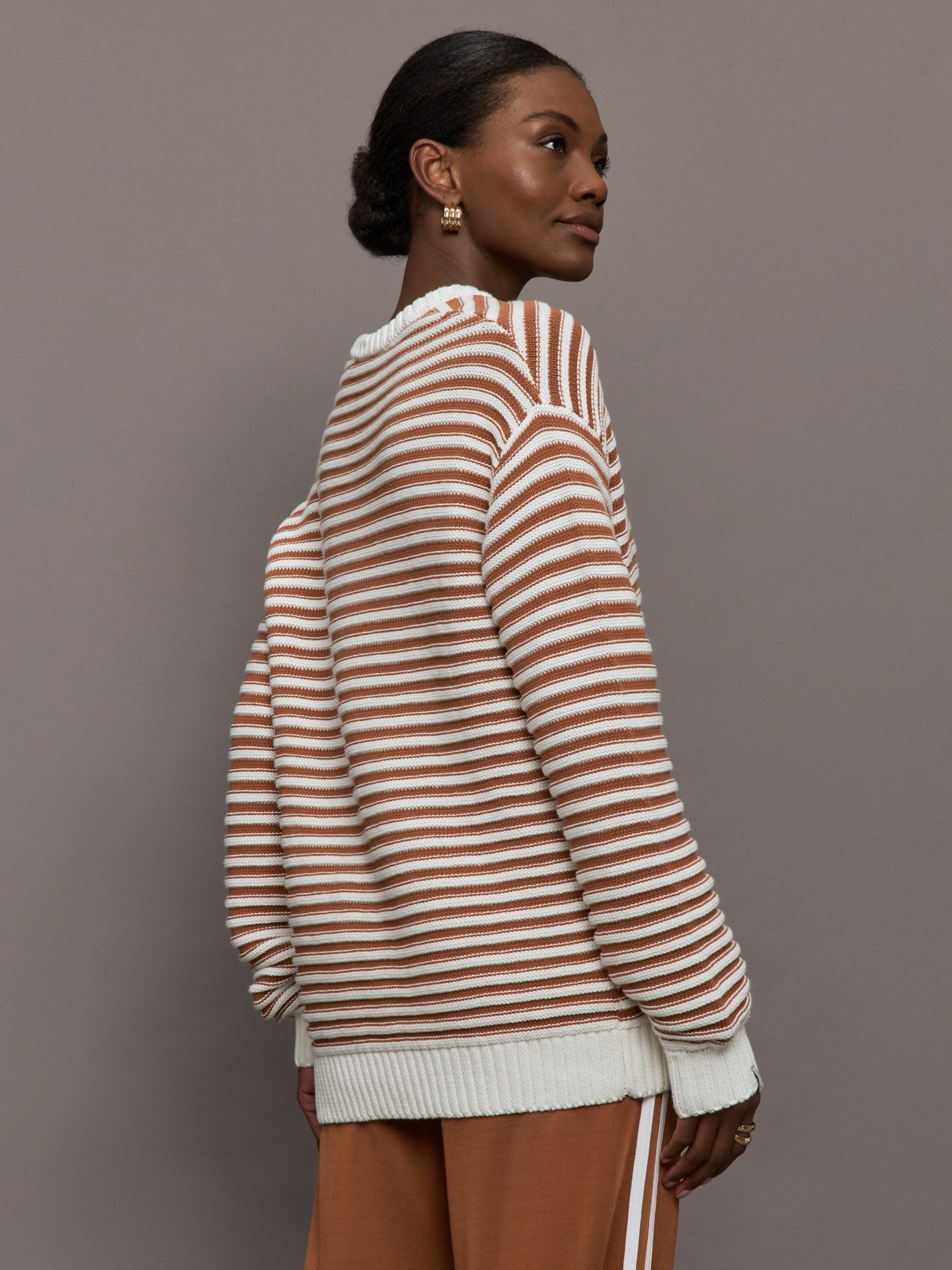 Model is wearing a brown/white horizontally striped oversized sweater.