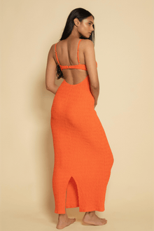 Tangerine slip dress with thin straps, open back cutout, and front slit, shown on model from behind.