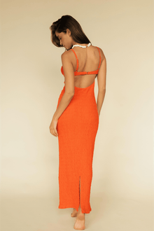 Tangerine slip dress with thin straps, open back, and textured fabric, modeled from behind with white neckline detail visible