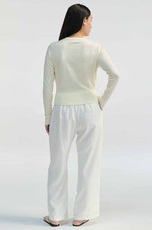 Woman wearing a white outfit on a plain background