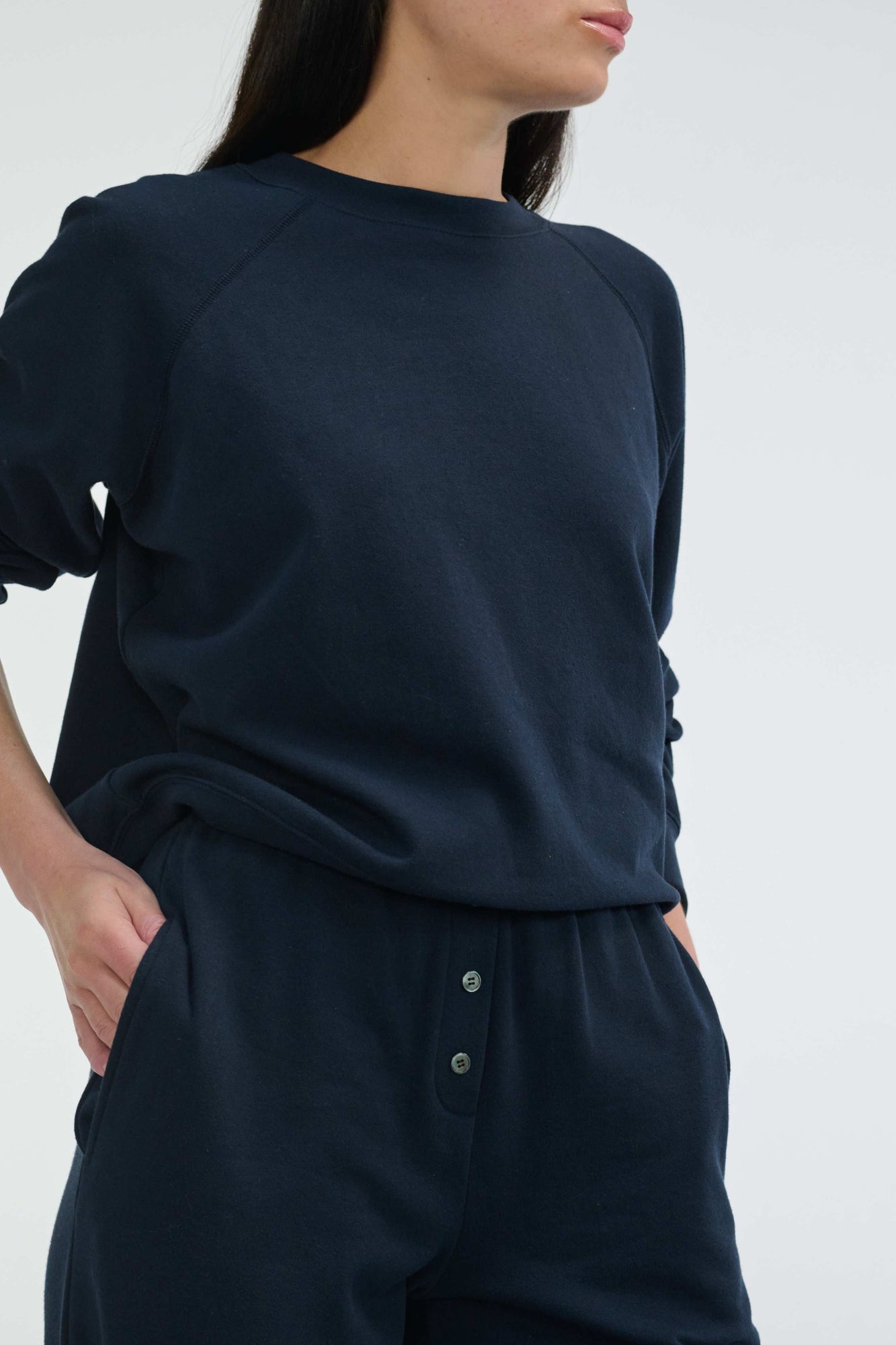 Person wearing a navy blue outfit with a plain background