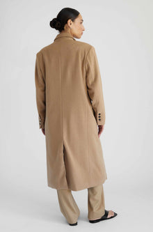 Woman wearing a beige coat on a white background