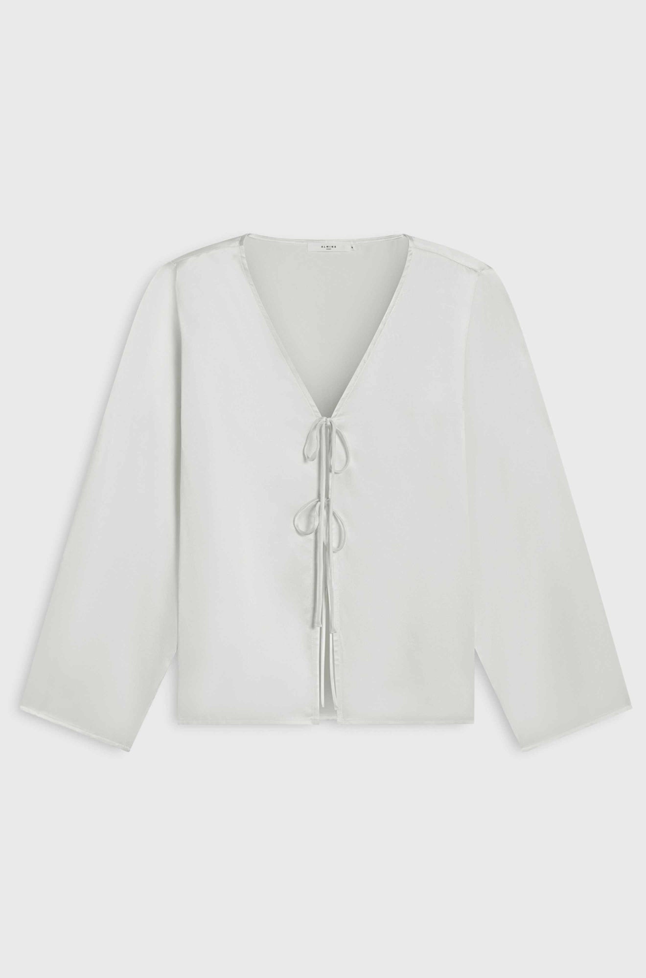 White blouse with a V-neck and long sleeves on a light gray background
