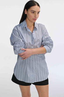 Woman wearing a blue striped shirt and black shorts on a white background