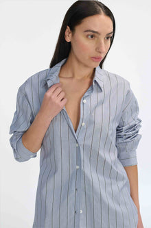 Woman wearing a black and navy striped shirt against a light background