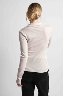 Woman wearing a pink button up top with black bottoms on a light grey background