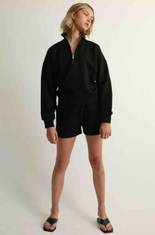 Woman wearing black shorts and a black sweatshirt
