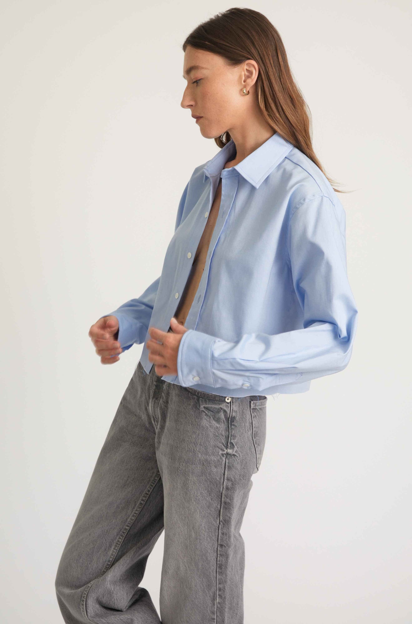 Person wearing a light blue shirt and gray pants against a white background