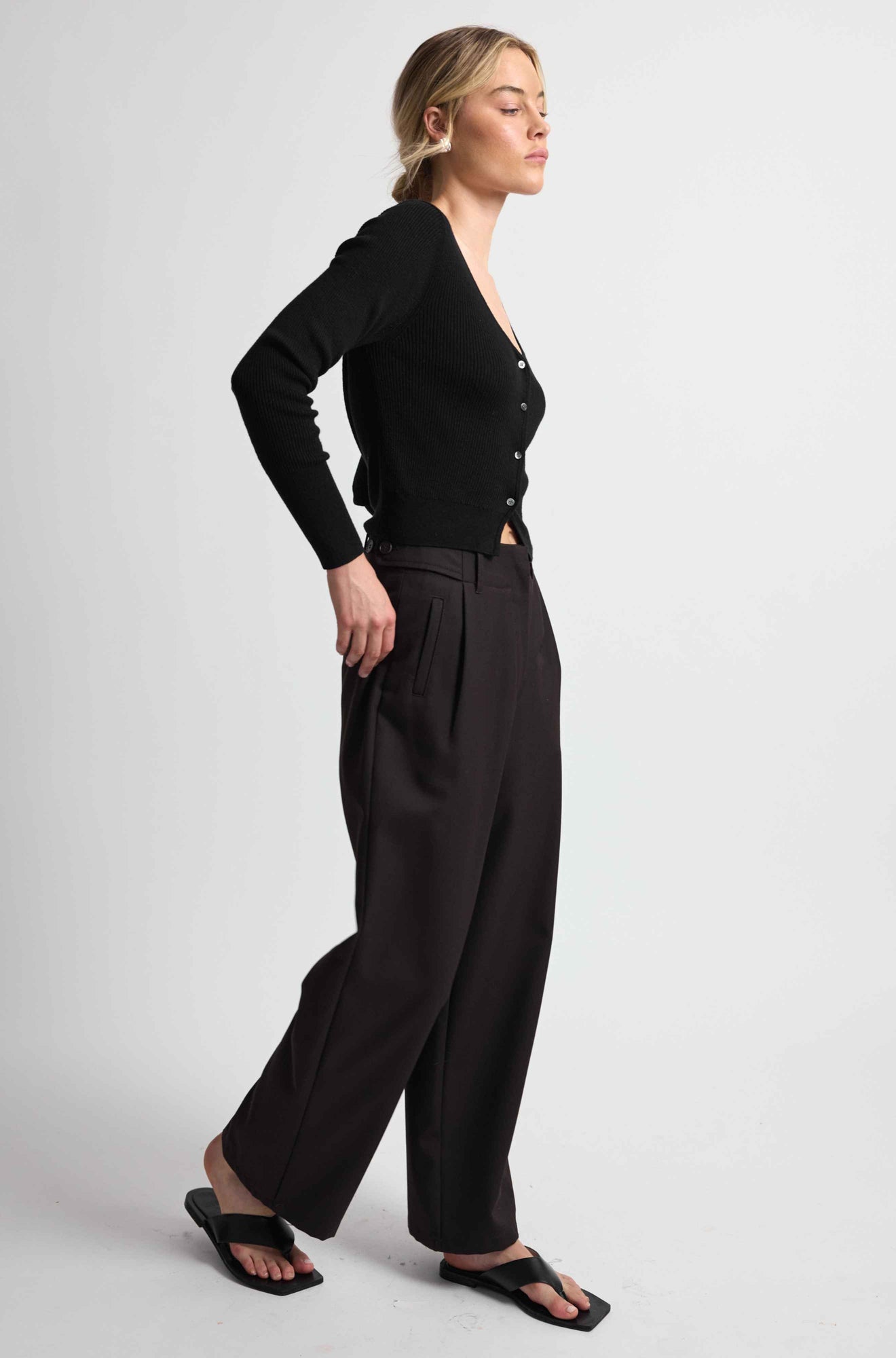 Woman wearing a black outfit with wide-leg pants on a white background