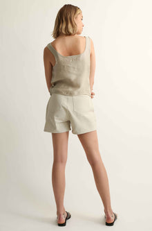 Woman wearing a beige tank top and shorts on a white background