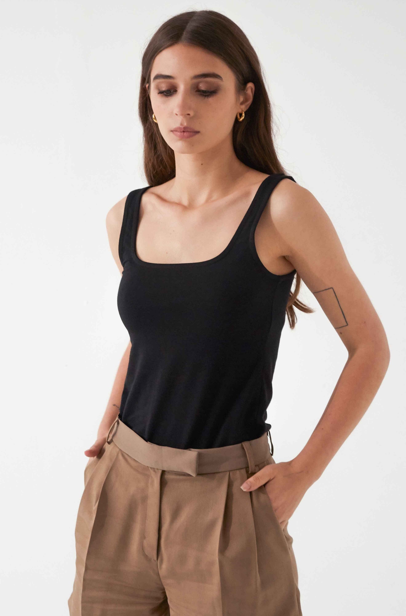 Woman wearing a black square tank top and brown pants